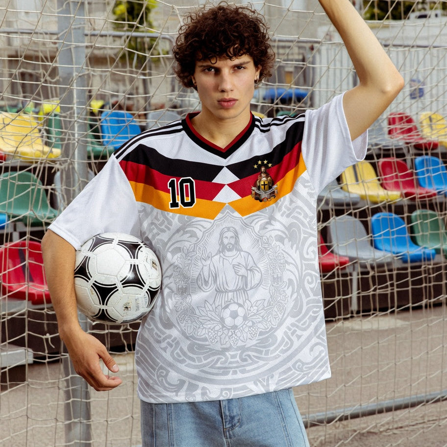 Front and back view of Germany 2026 home jersey in white with Jesus Christ graphics and German tricolor chevron stripes