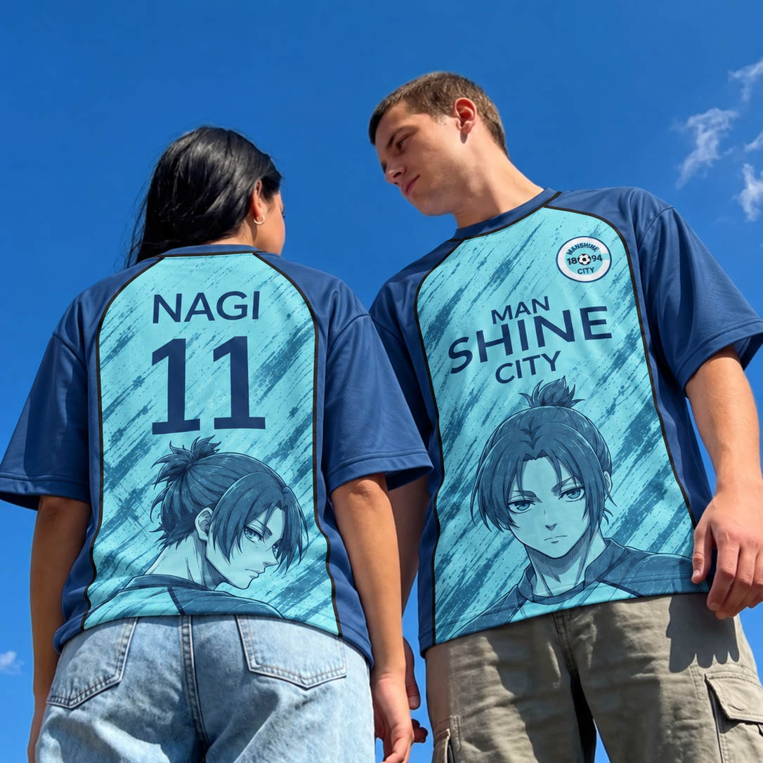 Two models wearing matching navy blue and light blue graphic t-shirts with anime character prints, shown from the back and front against a clear blue sky. Varldens Blue Lock Reo Mikage Manshine City Heritage Jersey featuring anime artwork and Manshine City crest.