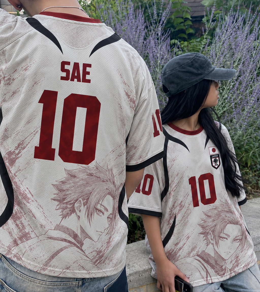 Two people wearing a Varldens matching white and red anime jersey-style shirts with the name SAE and number 10 on the back, standing outdoors in front of purple flowers and greenery. Varldens Japan Blue Lock Sae Itoshi Heritage Jersey featuring anime number 10 and JFA crest.